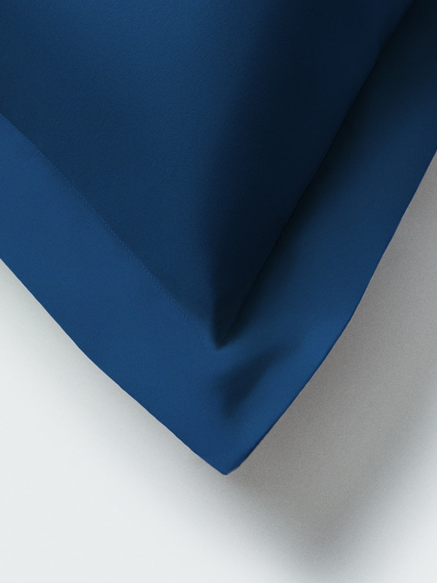 Part of a pillow with a Rivera Navy-colored pillowcase featuring embroidery along the edge.