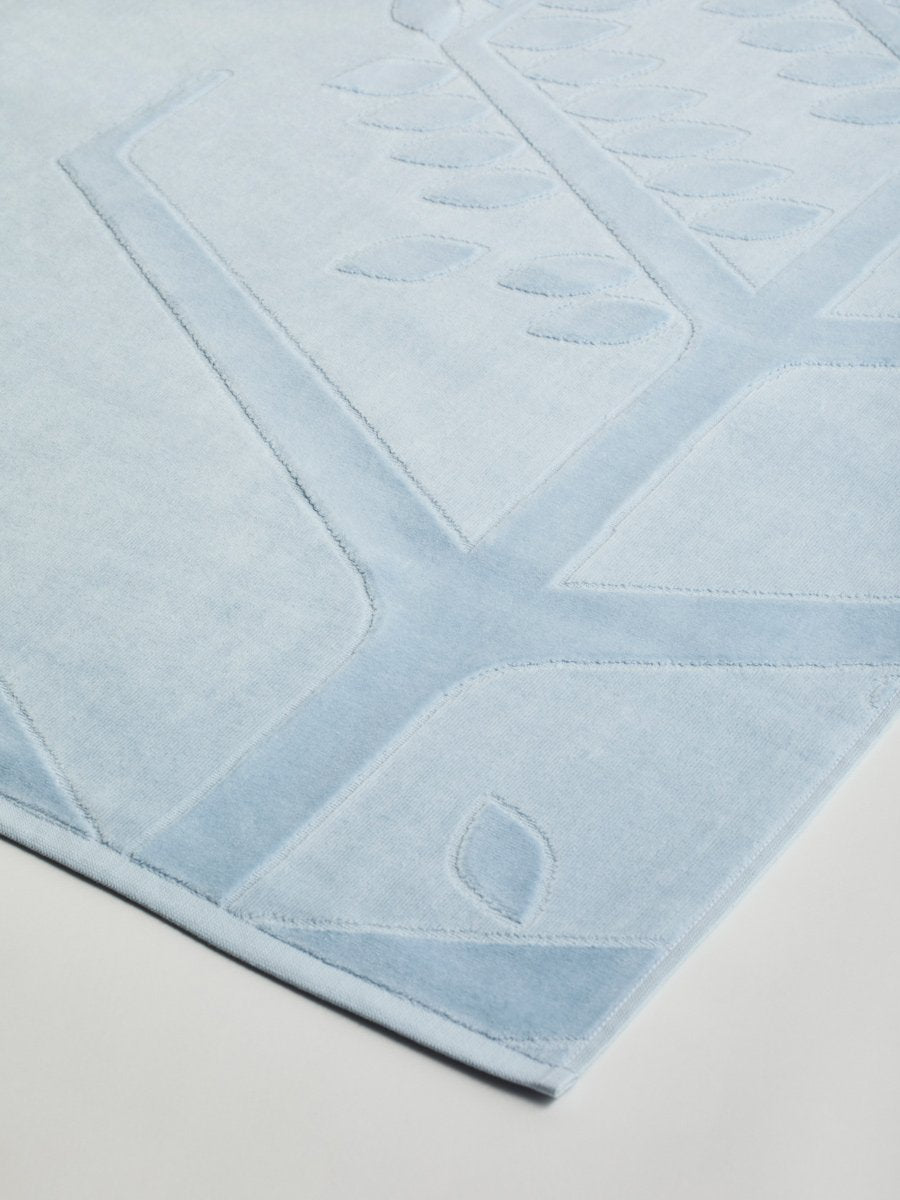 Close-up of a 'Maldivian Atoll' beach towel with a textured and embossed Four Seasons logo design.