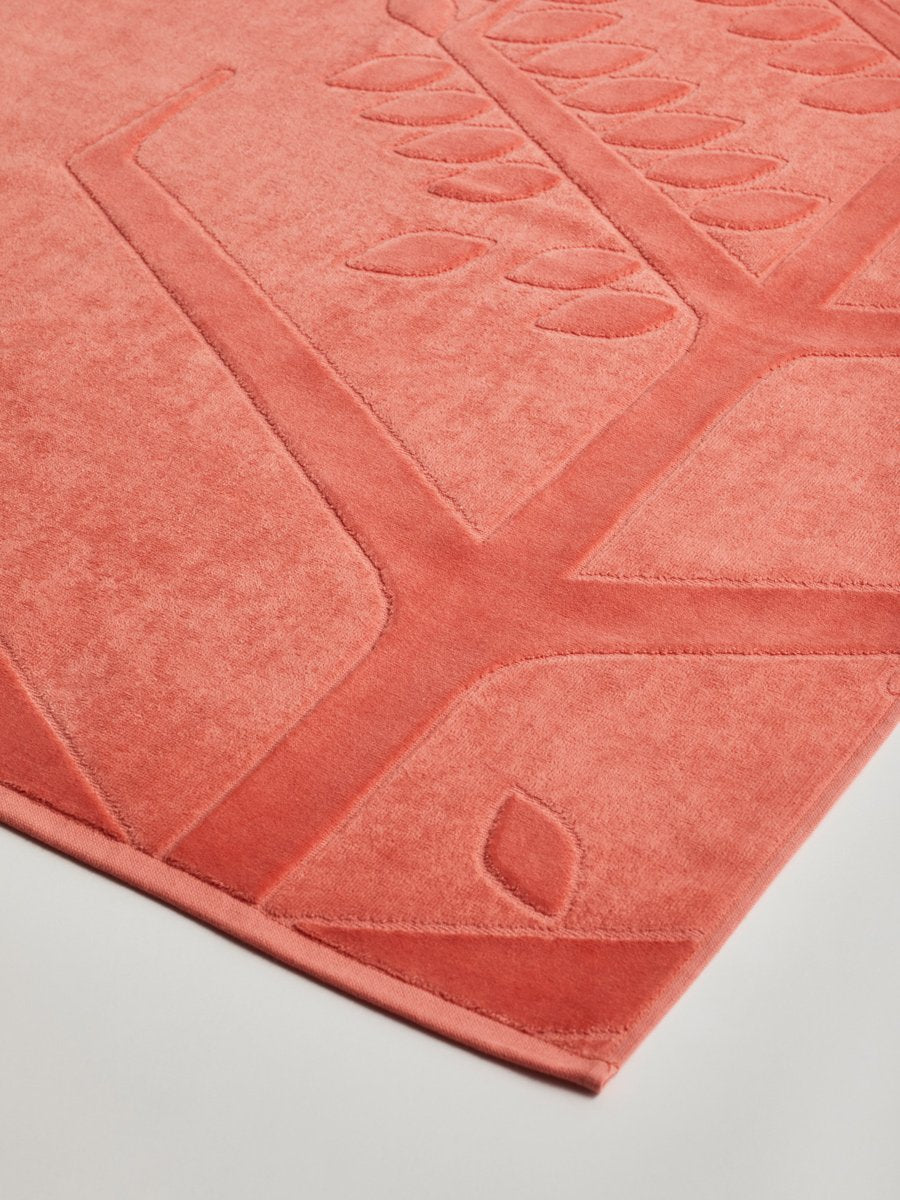 Close-up of a 'Red Sea Coral' beach towel with a textured and embossed Four Seasons logo design.