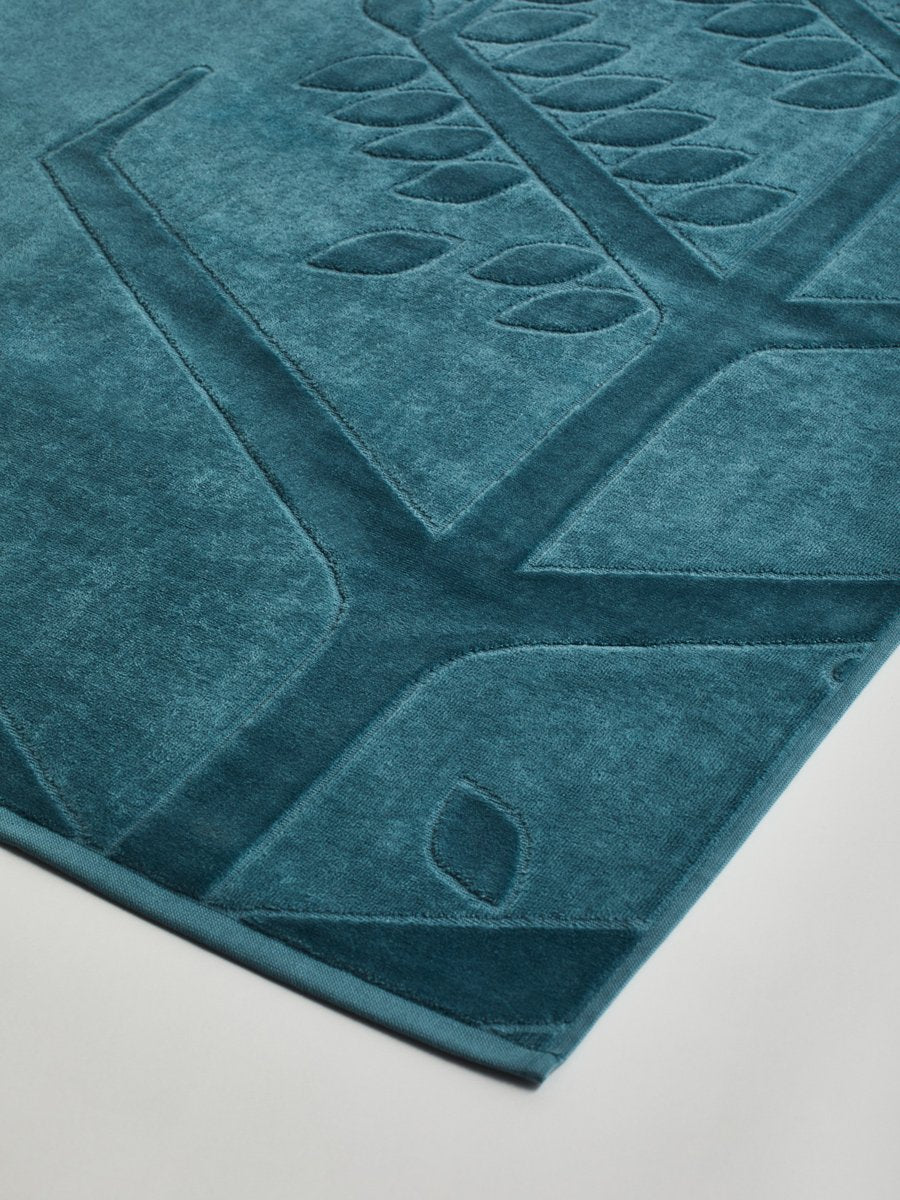 Close-up of a 'Polynesian Lagoon' beach towel with a textured and embossed Four Seasons logo design.