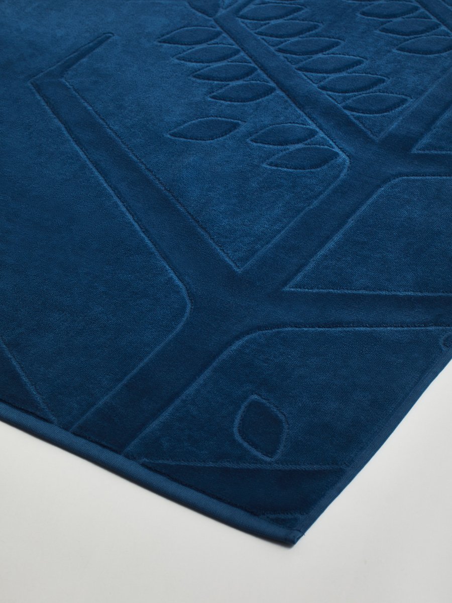Close-up of a 'Riviera Navy' beach towel with a textured and embossed Four Seasons logo design.