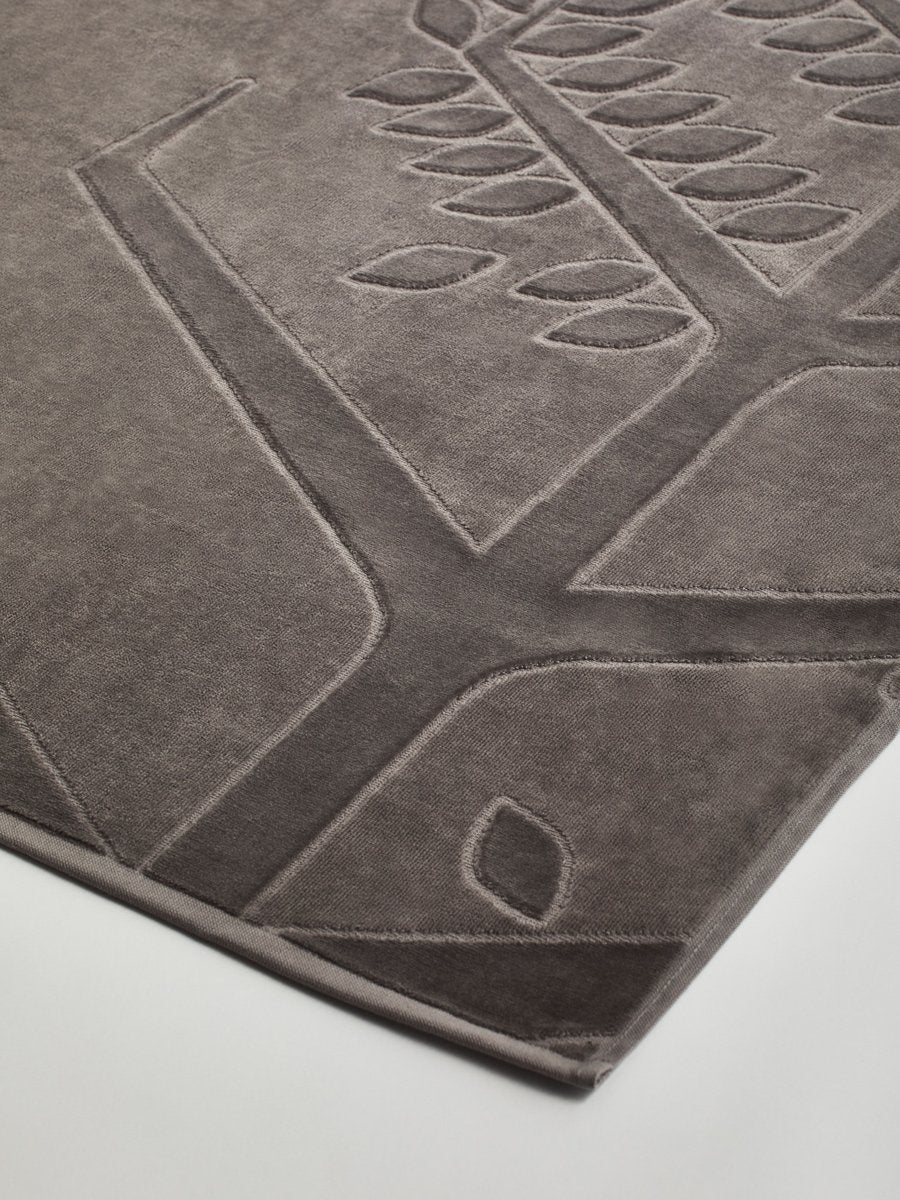 Close-up of a "Californian Driftwood" beach towel with a textured and embossed Four Seasons logo design.