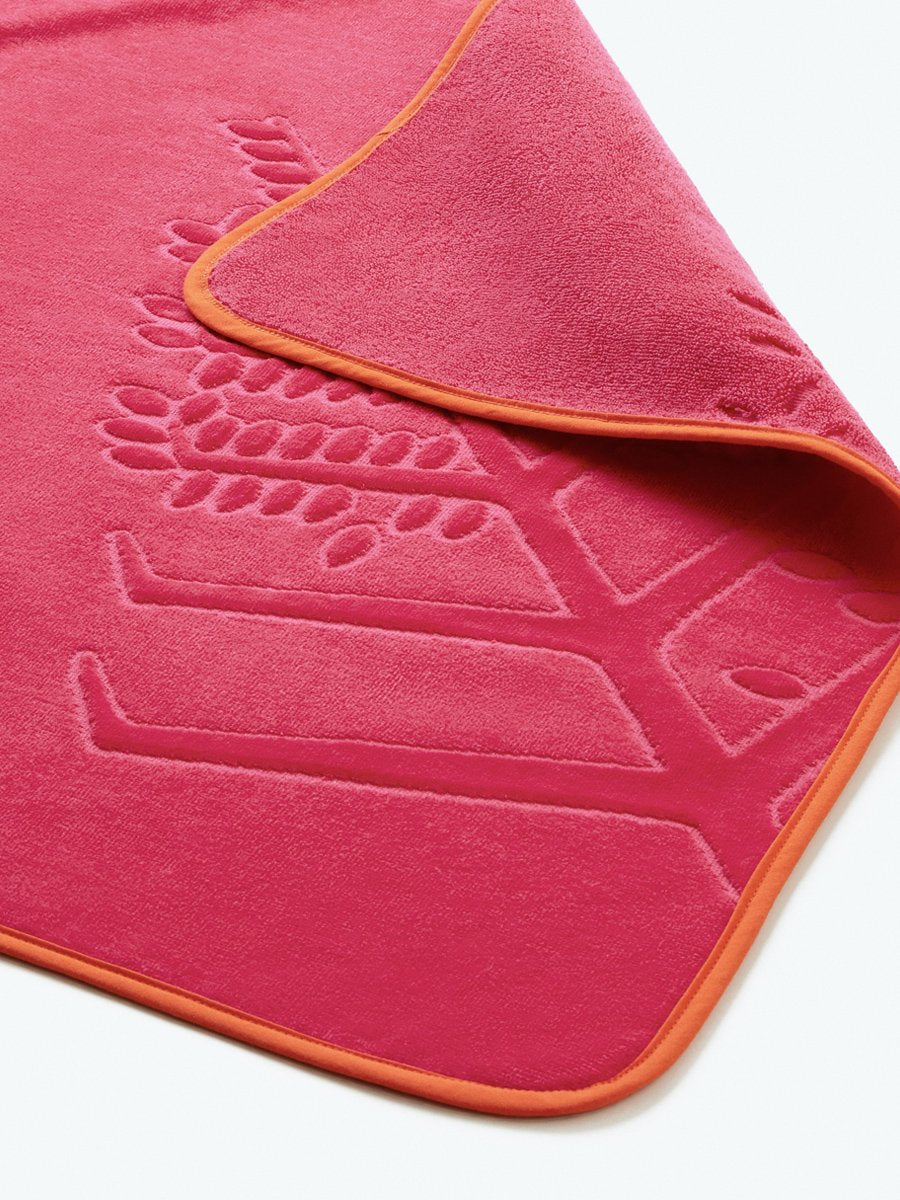 Close-up detail of a "Coral Reef Pink" hooded baby towel with a textured, embroidered Four Seasons logo.