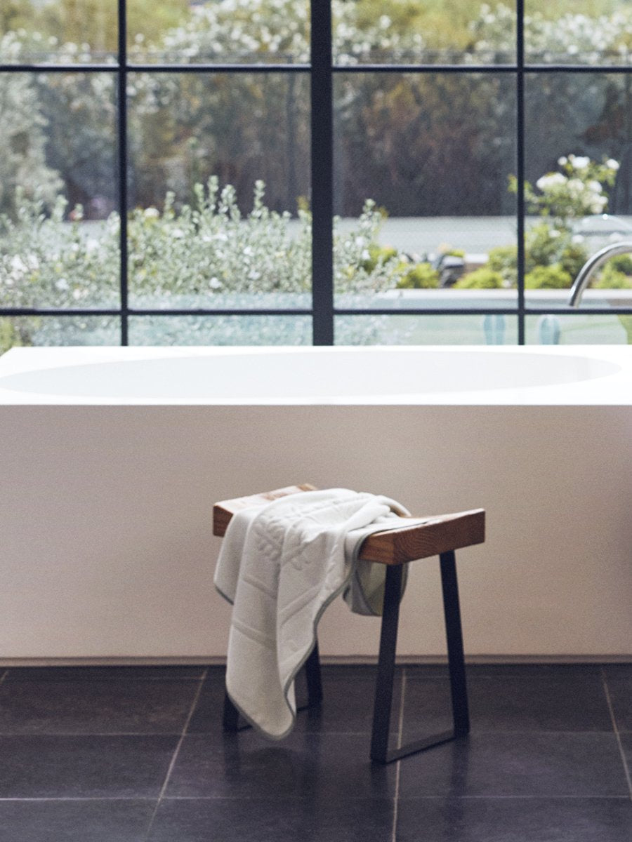 Baby towel in grey tones, placed on a wooden chair in a bright bathroom