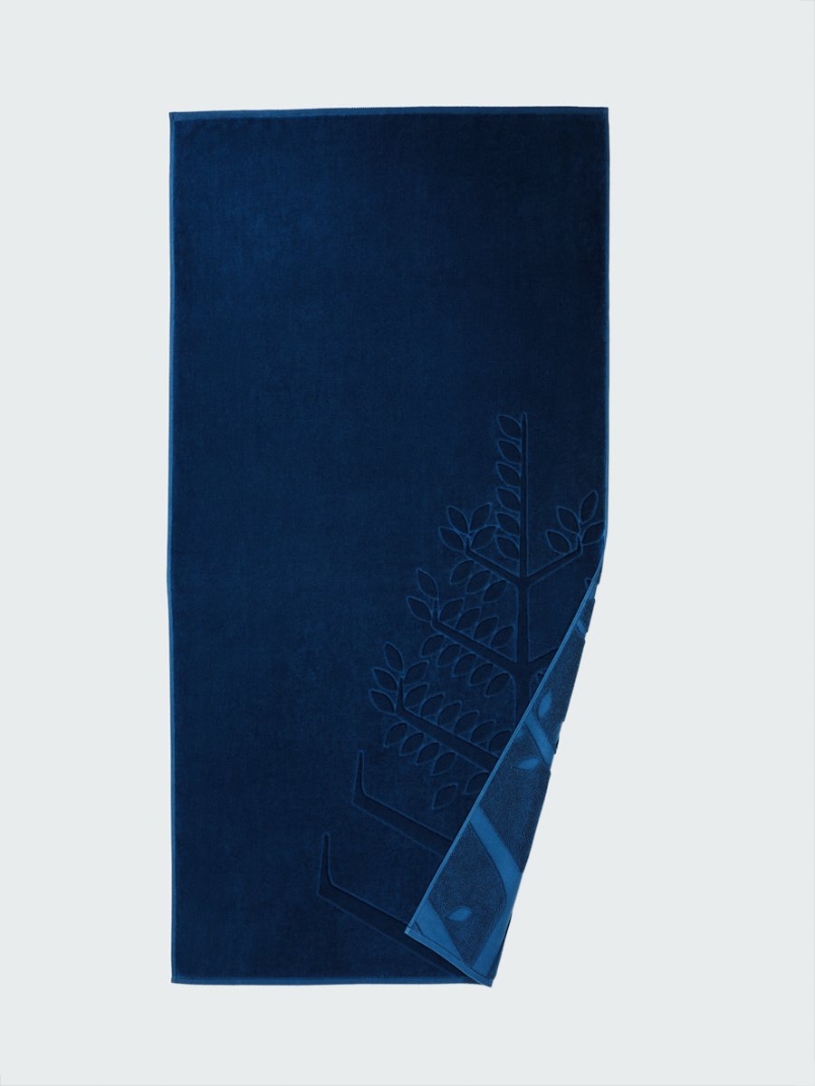 'Riviera Navy' beach towel with an embossed Four Seasons logo. Part of the towel is folded back to reveal the same design on the bottom.