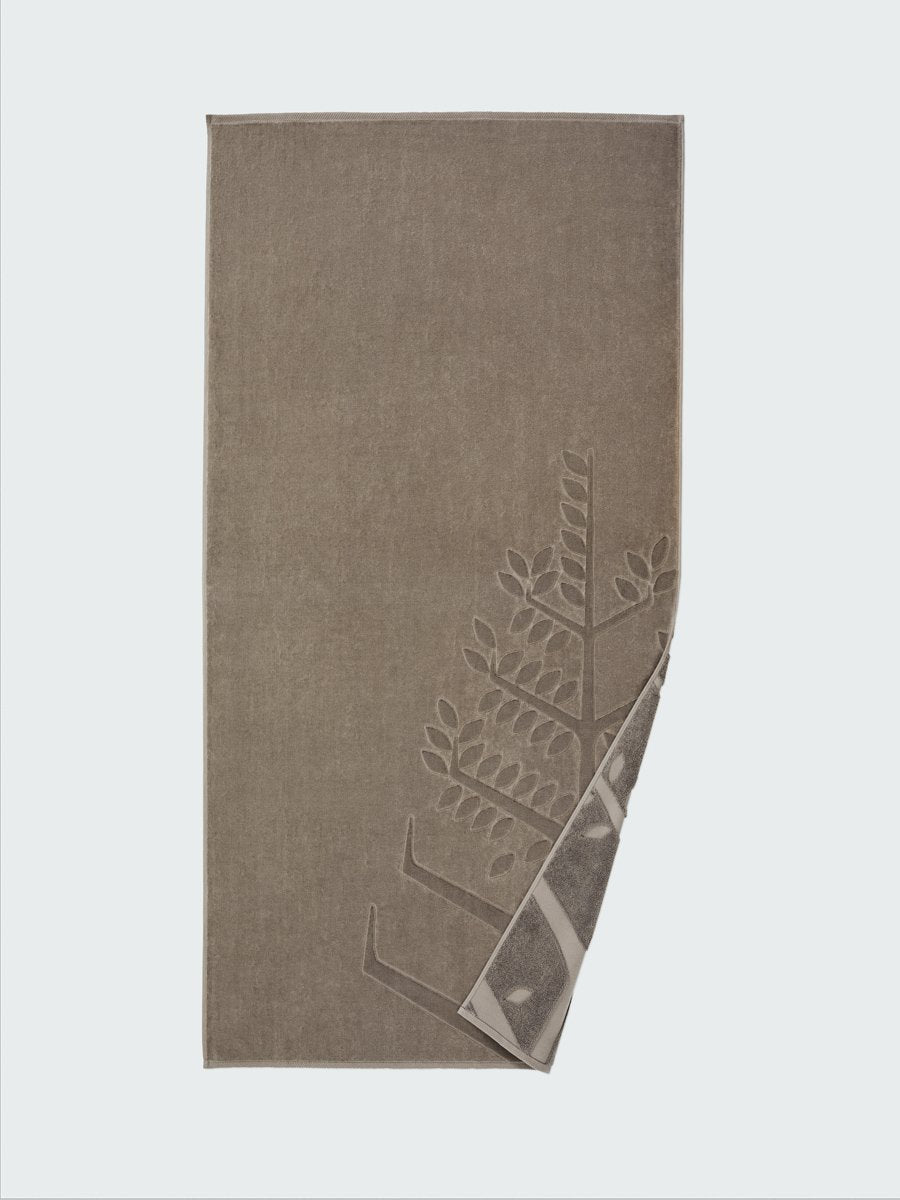 "California Driftwood" beach towel with an embossed Four Seasons logo. Part of the towel is folded back to reveal the same design on the bottom.