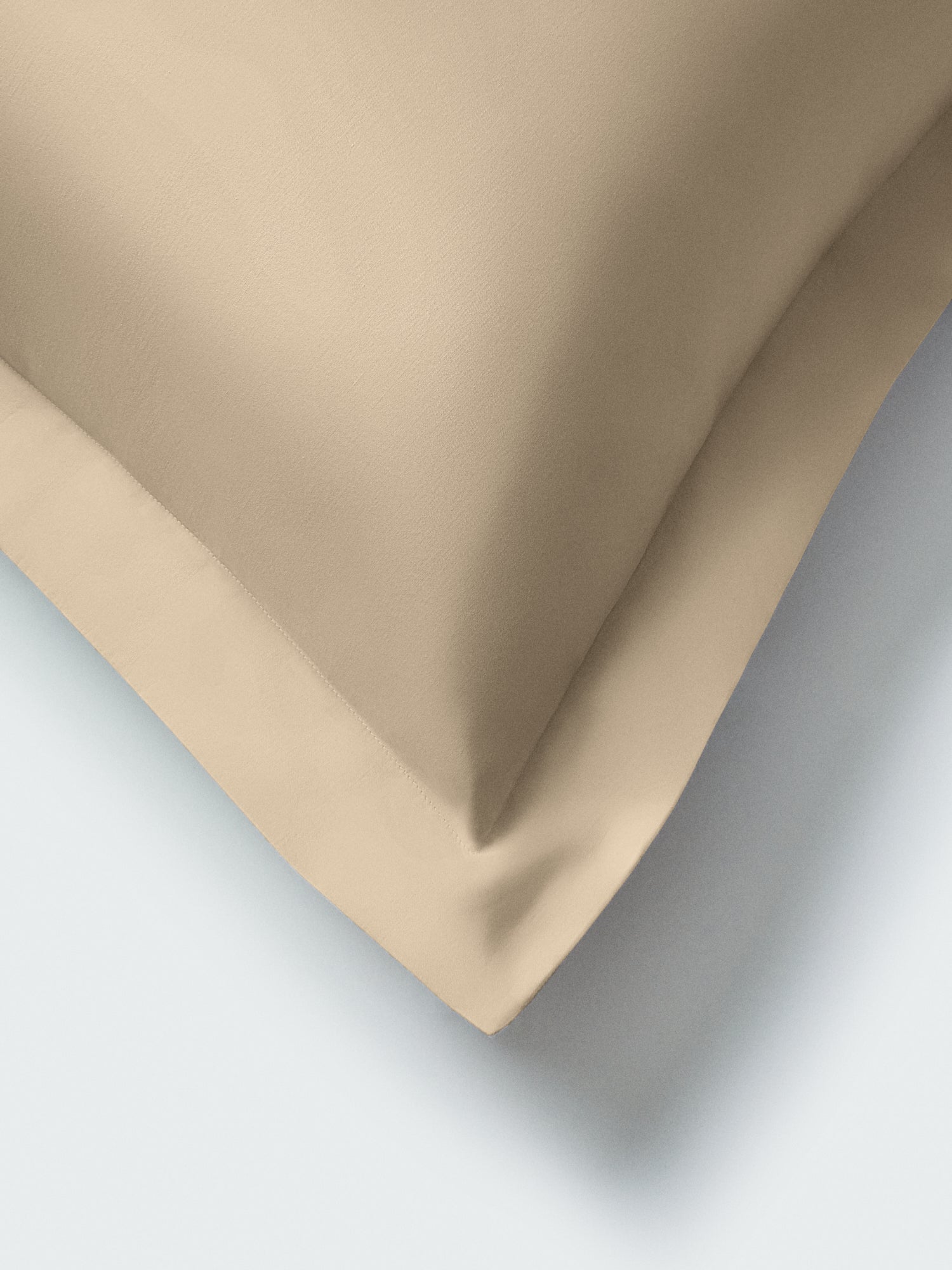 Part of a pillow with an Egyptian Camel color pillowcase featuring embroidery along the edge.