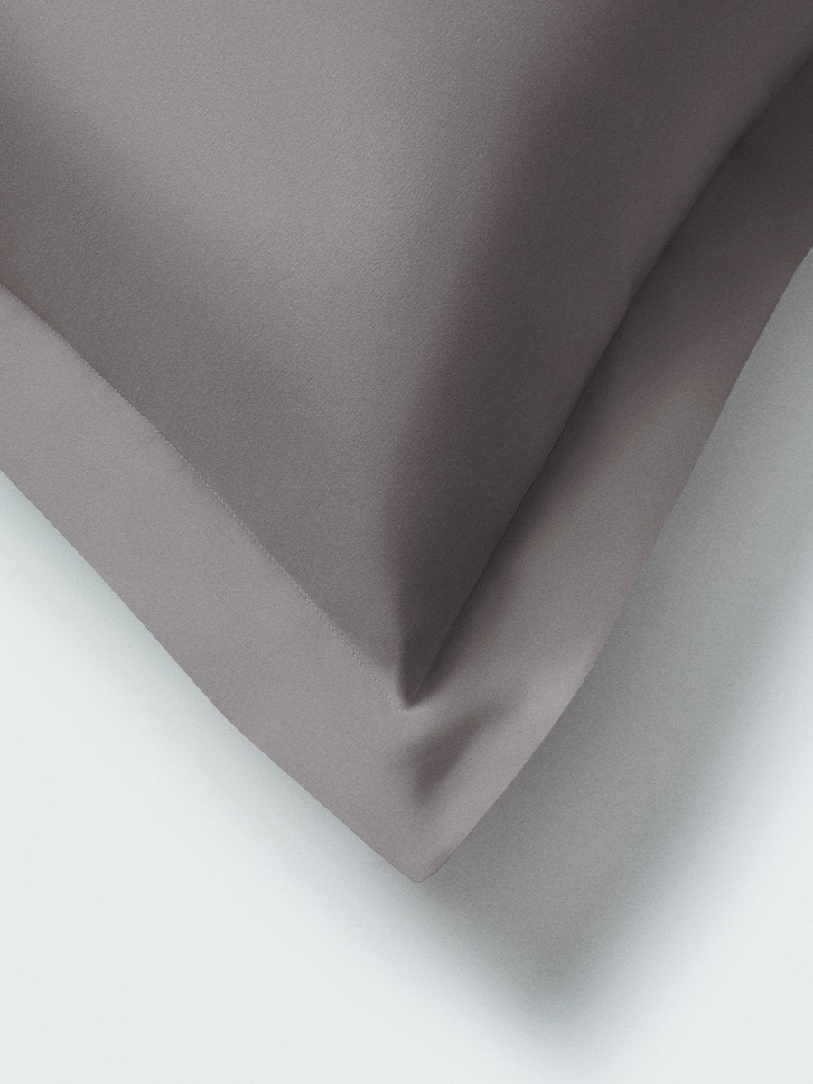 Part of a pillow with a Hampshire Charcoal color pillowcase featuring embroidery along the edge.
