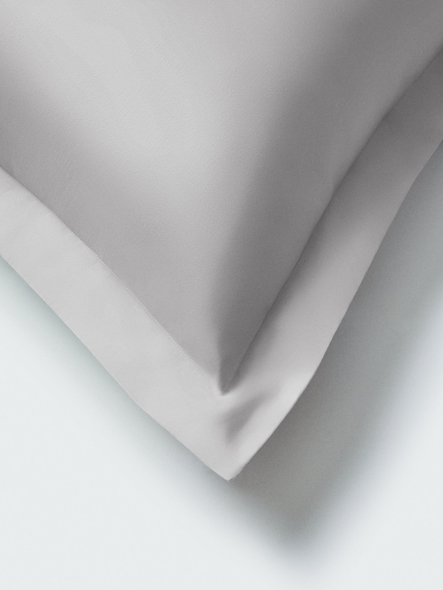 Part of a pillow with a Turkish Silver color pillowcase featuring embroidery along the edge.