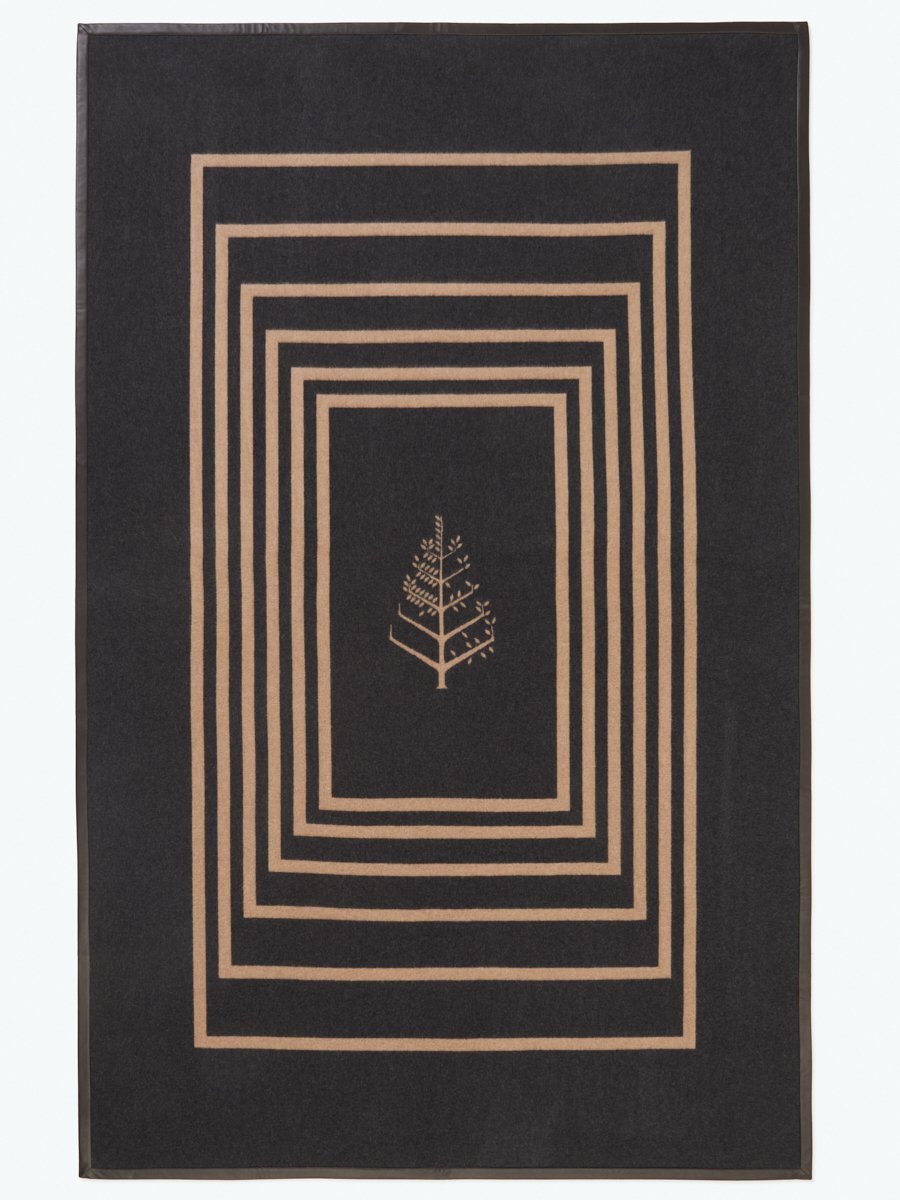 A black throw with a leather trim and a geometric pattern featuring the Four Seasons logo