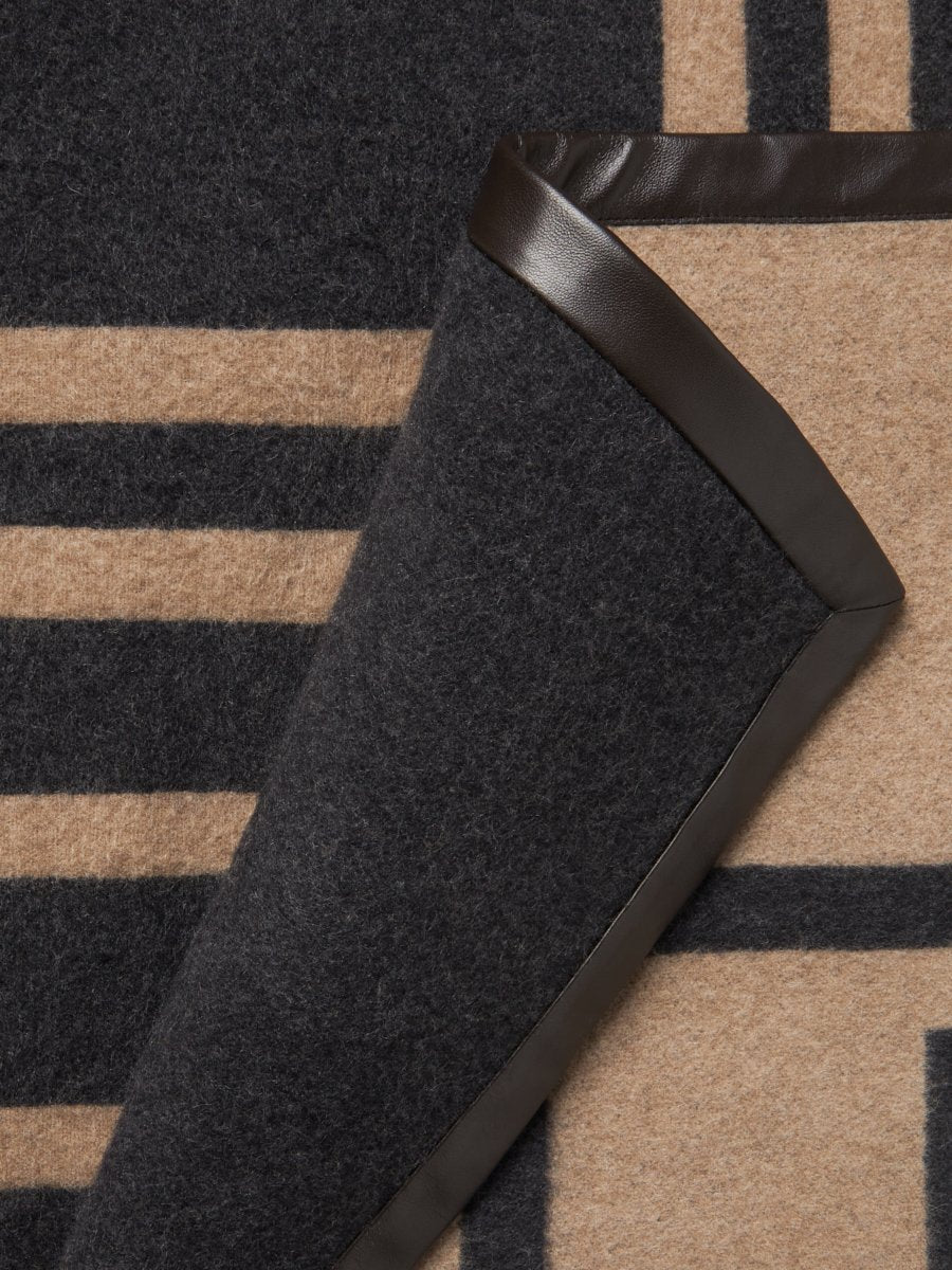 Close-up of the leather trim detail on a black cashmere throw.