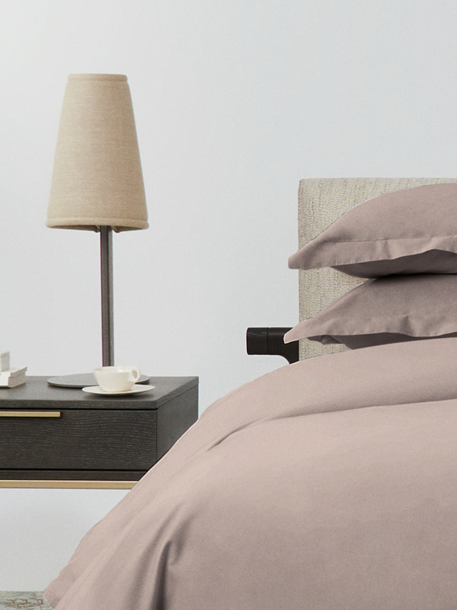 Bed dressed with a duvet in Moroccan Sand color and two pillows with embroidery along the edge.