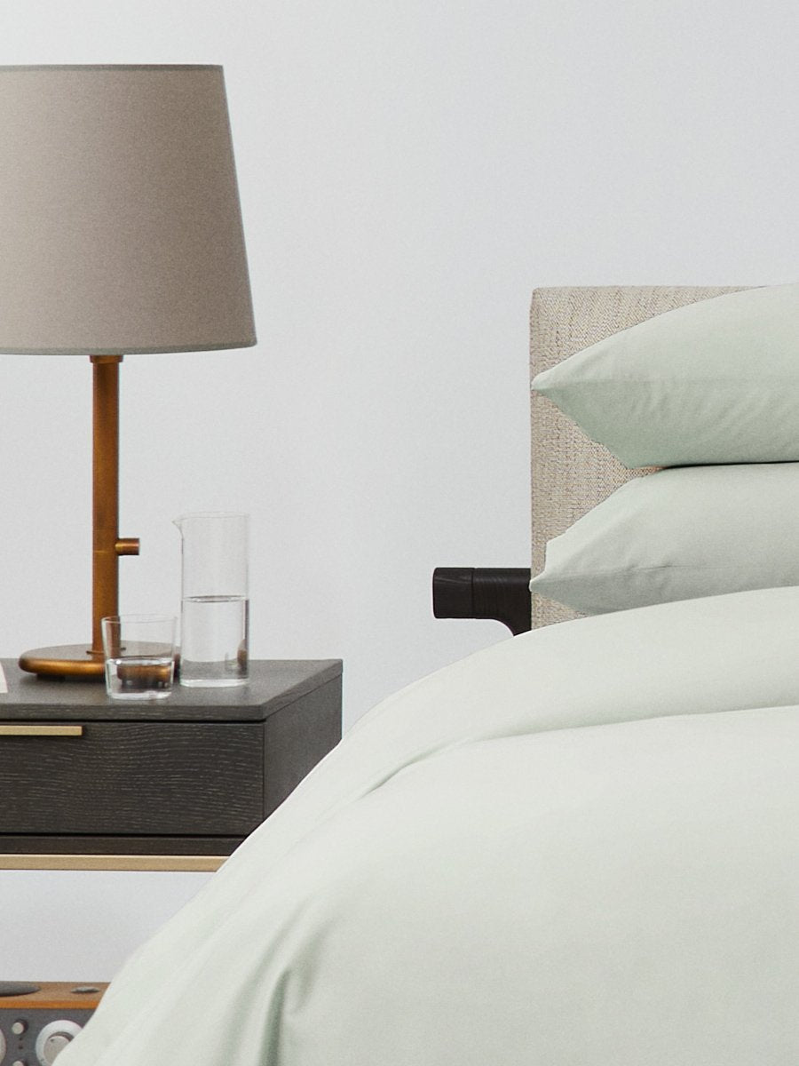 Bed dressed with a duvet in Florentine Sage color and two matching pillows.