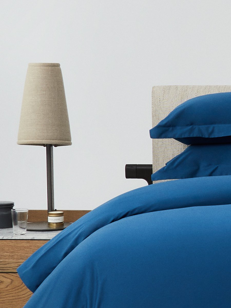 Bed dressed with a duvet in Riviera Navy color and two pillows with embroidery along the edge.