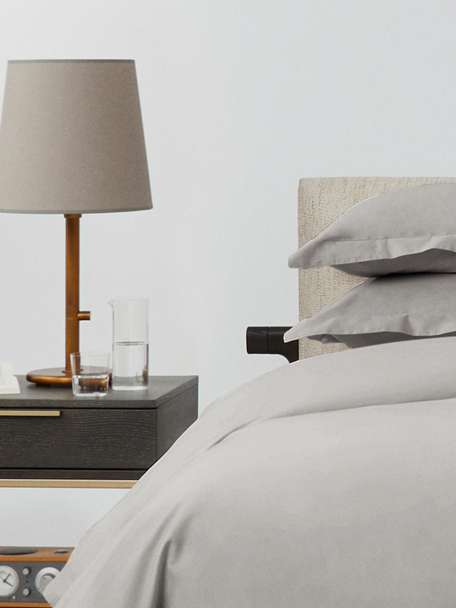 Bed dressed with a duvet in Spanish Slate color and two pillows with embroidery along the edge.
