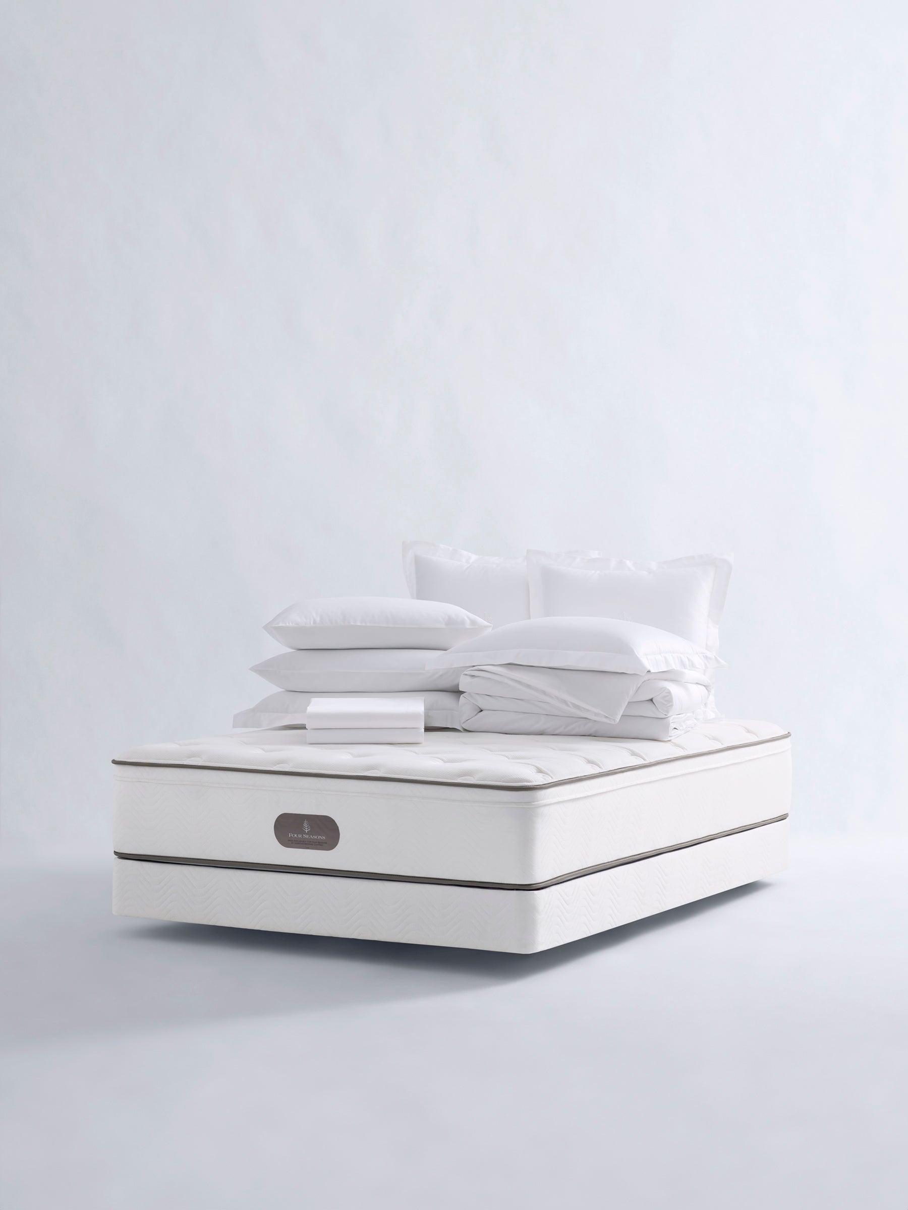 Four Seasons Bedding Set. The set includes a white mattress, a white comforter, and several white pillows, all neatly arranged on a white background.