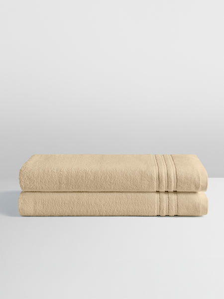 Two folded bath sheets in a warm, luxurious Egyptian Camel color, stacked neatly on a white surface.