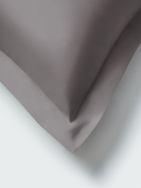 Part of a pillow with a Hampshire Charcoal color pillowcase featuring embroidery along the edge.