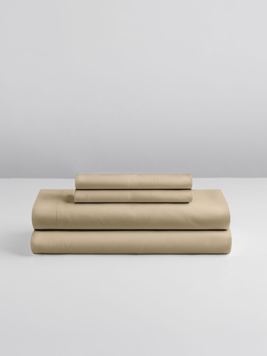 A set of Egyptian Camel-colored sheets, folded into perfect rectangles and stacked on a flat surface.