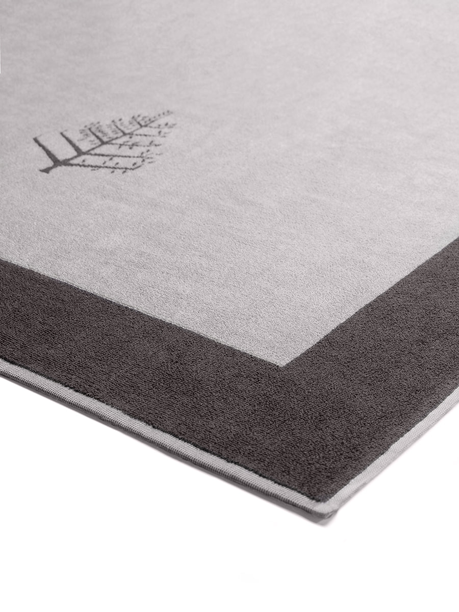 Close-up of a "Hampshire Charcoal" Resort Towel with a subtle embroidered Four Seasons logo.  The towel features a darker border