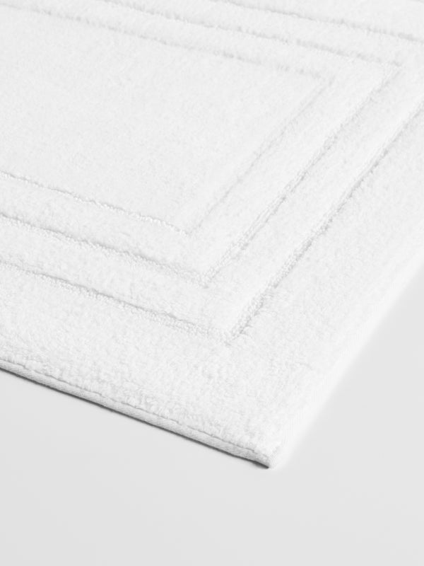 Luxurious white bath mat with a triple frame design and a plush, soft texture.
