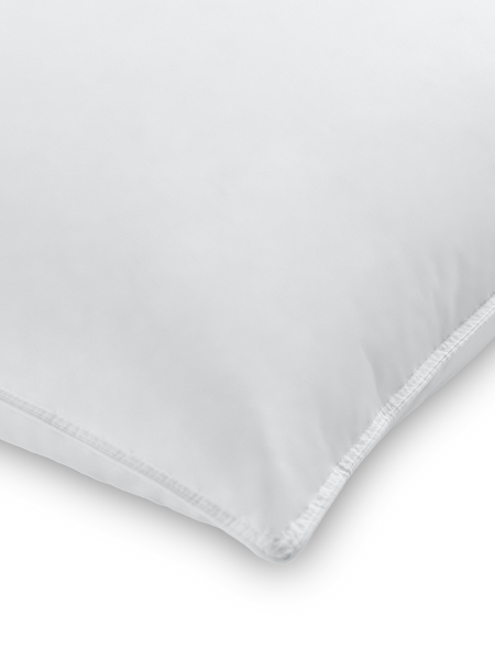 Part of a pillow with a Signature White color pillowcase featuring a thin embroidery along the edge.