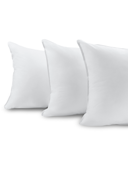 Three fluffy white pillows, stacked one on top of the other.