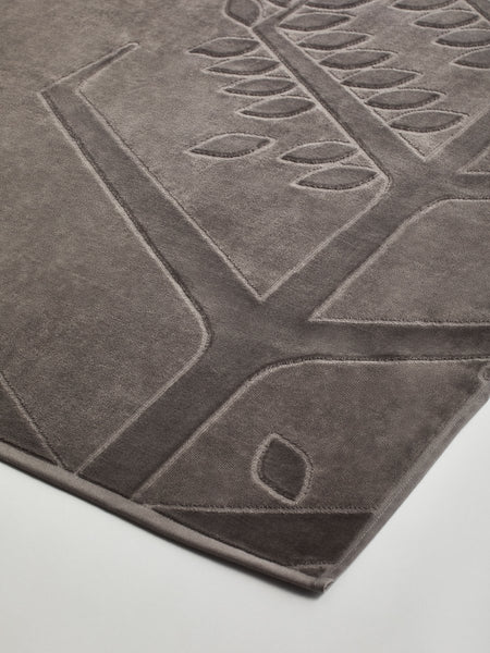 Close-up of a "Californian Driftwood" beach towel with a textured and embossed Four Seasons logo design.