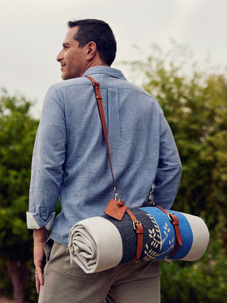 An Al Fresco Blanket rolled up with a leather travel strap and handle.