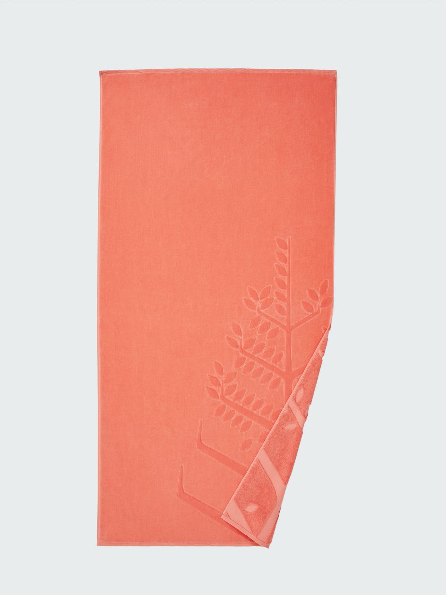  'Red Sea Coral' beach towel with an embossed Four Seasons logo. Part of the towel is folded back to reveal the same design on the bottom.
