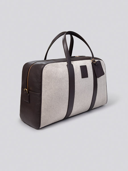 The Bowler travel bag, a versatile and stylish carry-on with a sleek design, crafted from Italian Pebble Grain Leather and Organic Cotton Toile.