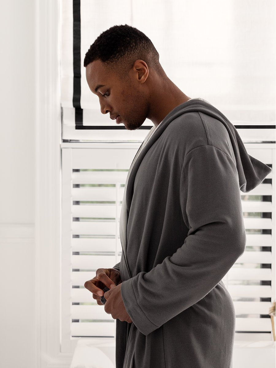 The men's hooded gown features a mid-length design with a bamboo cotton interior for exceptional softness and comfort. The exterior features a Hampshire Charcoal hue in a neutral colorway.
