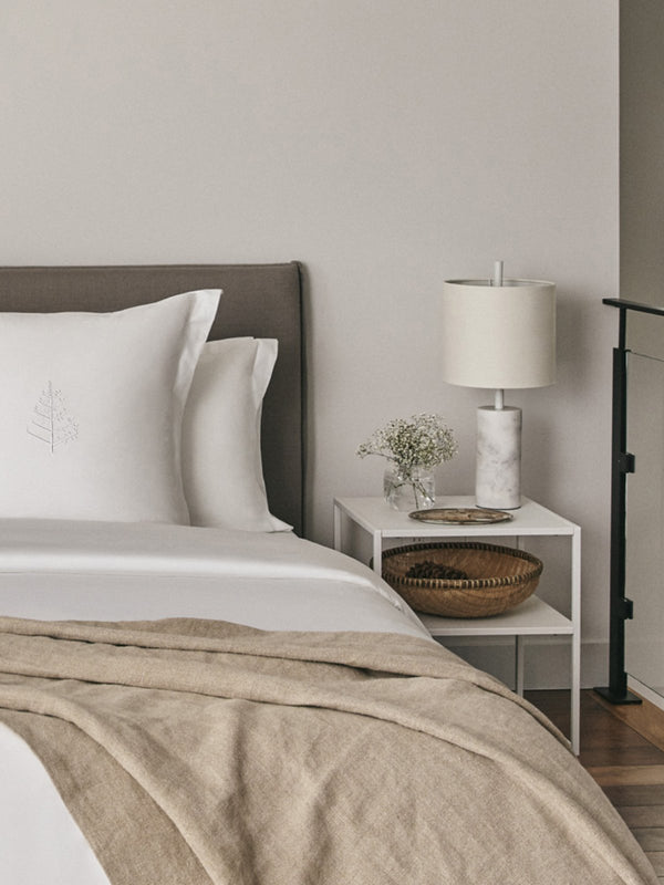 A beautifully made bed showcasing a crisp white duvet and a cozy throw blanket.