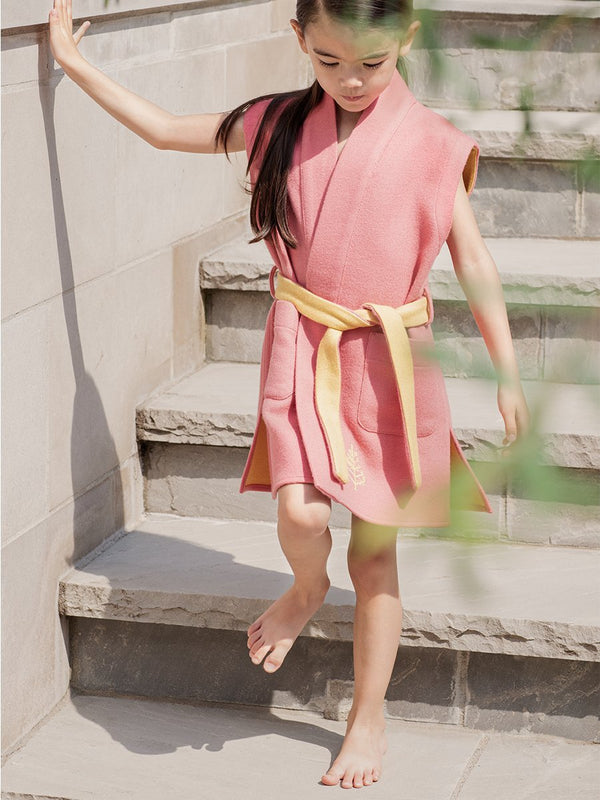 Little girl dressed in a Four Seasons Resort children's robe, sleeveless, light wool, pink with yellow interior, elegant and stylish