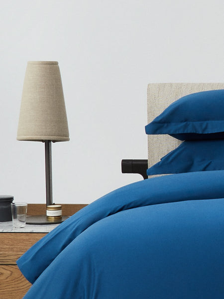 Bed dressed with a duvet in Riviera Navy color and two pillows with embroidery along the edge.